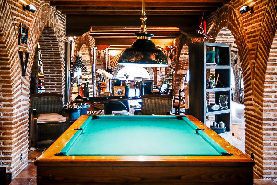 Interior of El Despeñadero Lodge featuring a billiard table, rustic brick arches, and cozy seating areas, highlighting the estate's inviting atmosphere for wingshooting enthusiasts.