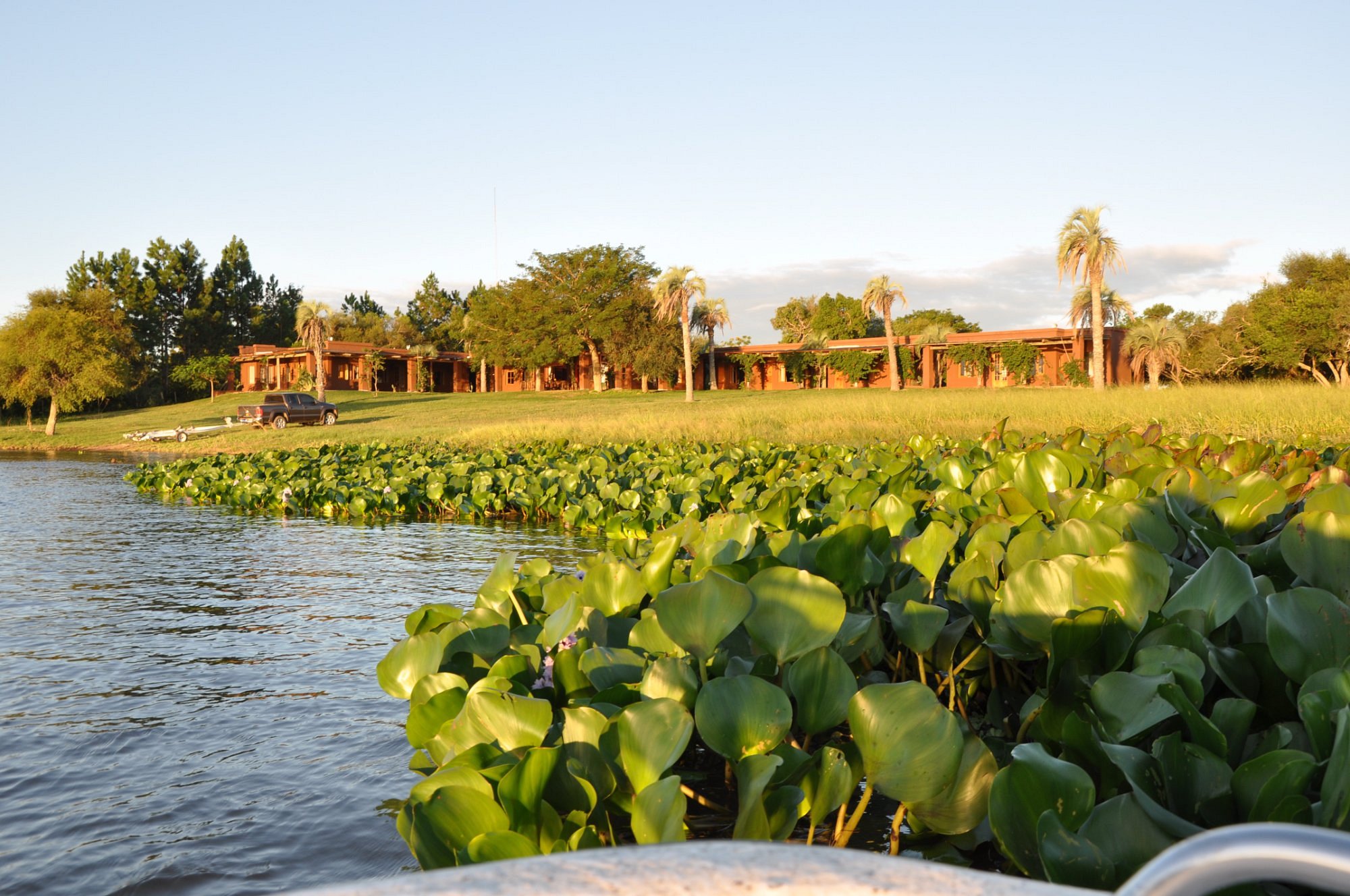 Luxury Don Joaquín River Lodge surrounded by lush greenery and water lilies, located near Esquina, Argentina, offering a serene fishing destination.