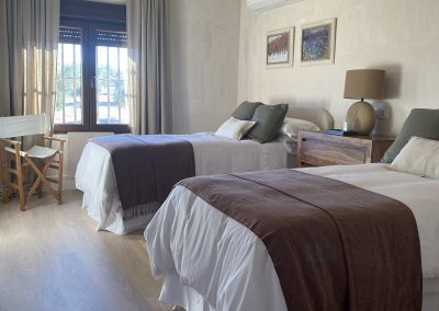 Cozy twin-bedded room at El Despeñadero Lodge, featuring natural light, elegant decor, and a view of the surrounding landscape, ideal for guests after a day of wingshooting adventures.