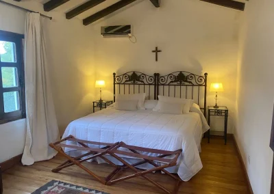 Cozy bedroom at El Palomar Hunting Lodge featuring two beds, wooden beams, and warm lighting, highlighting the lodge's blend of traditional Argentine charm and modern comfort.