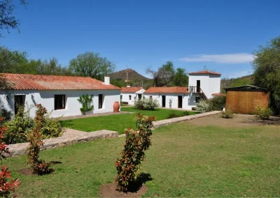 El Palomar Hunting Lodge in Argentina, featuring traditional white buildings, lush green lawns, and a blue sky, highlighting the lodge's welcoming atmosphere and natural surroundings.