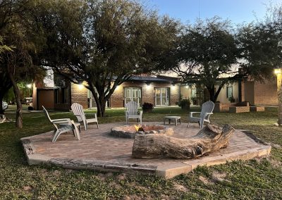 Cozy outdoor fire pit area with wooden seating, surrounded by trees, at Estancia La Emilia, a premier hunting destination in Argentina.