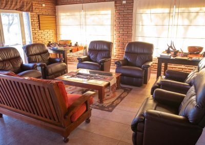 Cozy lounge area at Estancia La Emilia featuring leather recliners and wooden furniture, designed for relaxation after pigeon and dove hunting adventures.