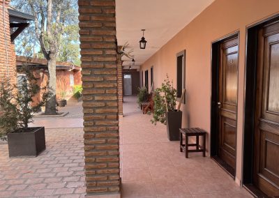 Corridor of Estancia La Emilia showcasing rustic architecture, wooden doors, and potted plants, reflecting the luxurious accommodations available for pigeon and dove hunting guests.