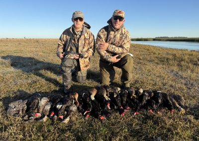Hunters posing with a collection of ducks after a successful hunt at La Paz duck hunting lodge in Argentina, showcasing the Pampas waterfowl experience.