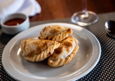 Delicious Argentine empanadas served on a plate with dipping sauce, highlighting traditional cuisine at Estancia Las Palomas lodge.