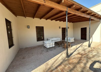 Luxurious outdoor seating area at Las Tapias dove hunting retreat, featuring comfortable white furniture under a wooden pergola, showcasing the lodge's exclusive accommodations in Argentina.