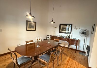 Elegant dining area in Las Tapias lodge, featuring a wooden table, vintage chairs, decorative wall art, and soft lighting, reflecting the refined atmosphere of the exclusive dove hunting retreat in Argentina.