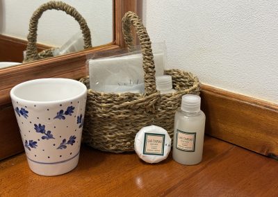 Bathroom amenities including a ceramic cup with floral design, a woven basket containing toiletries, and a mirror, reflecting the lodge's refined accommodations at Las Tapias dove hunting retreat.