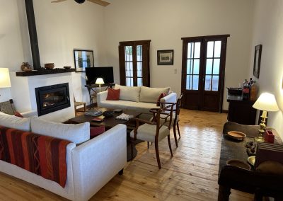 Cozy living area of Las Tapias dove hunting lodge featuring modern furnishings, a fireplace, and large windows, highlighting the retreat's luxurious accommodations and inviting atmosphere.
