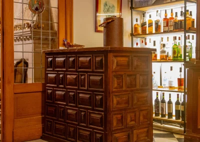 Wooden bar counter with decorative paneling, surrounded by shelves displaying various bottles of spirits, in the luxurious Estancia Santa Rita lodge, Argentina.