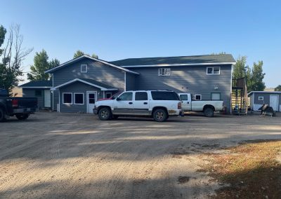 Spacious lodge for hunters at Lucky Lake, featuring vehicles parked outside, surrounded by a rustic prairie landscape.