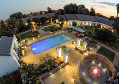 Aerial view of a luxury lodge in South Africa featuring a swimming pool, landscaped garden, and outdoor seating area, ideal for relaxation after wingshooting adventures.