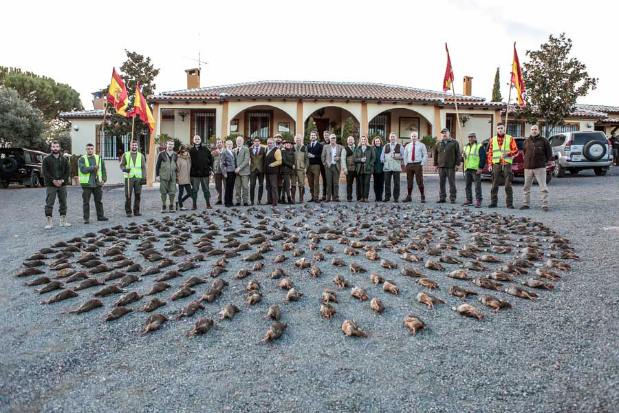 Group of hunters and staff at El Despeñadero lodge in Spain, posing with a display of harvested red-legged partridges, showcasing the traditional wingshooting experience.