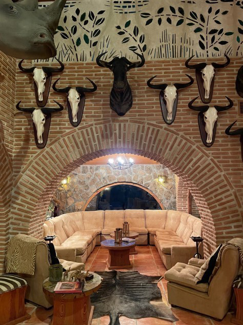 Cozy lounge area in El Despeñadero shooting estate featuring curved seating, rustic brick walls, and decorative animal skulls, reflecting the traditional Spanish hunting ambiance.