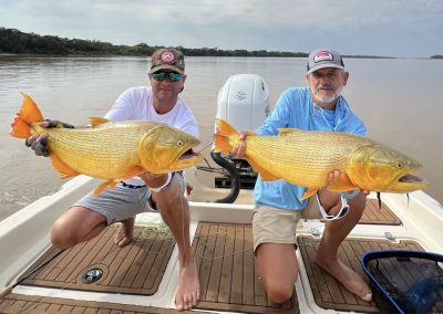 Anglers displaying Golden Dorado fish catch on river boat at Don Joaquín River Lodge in Argentina.